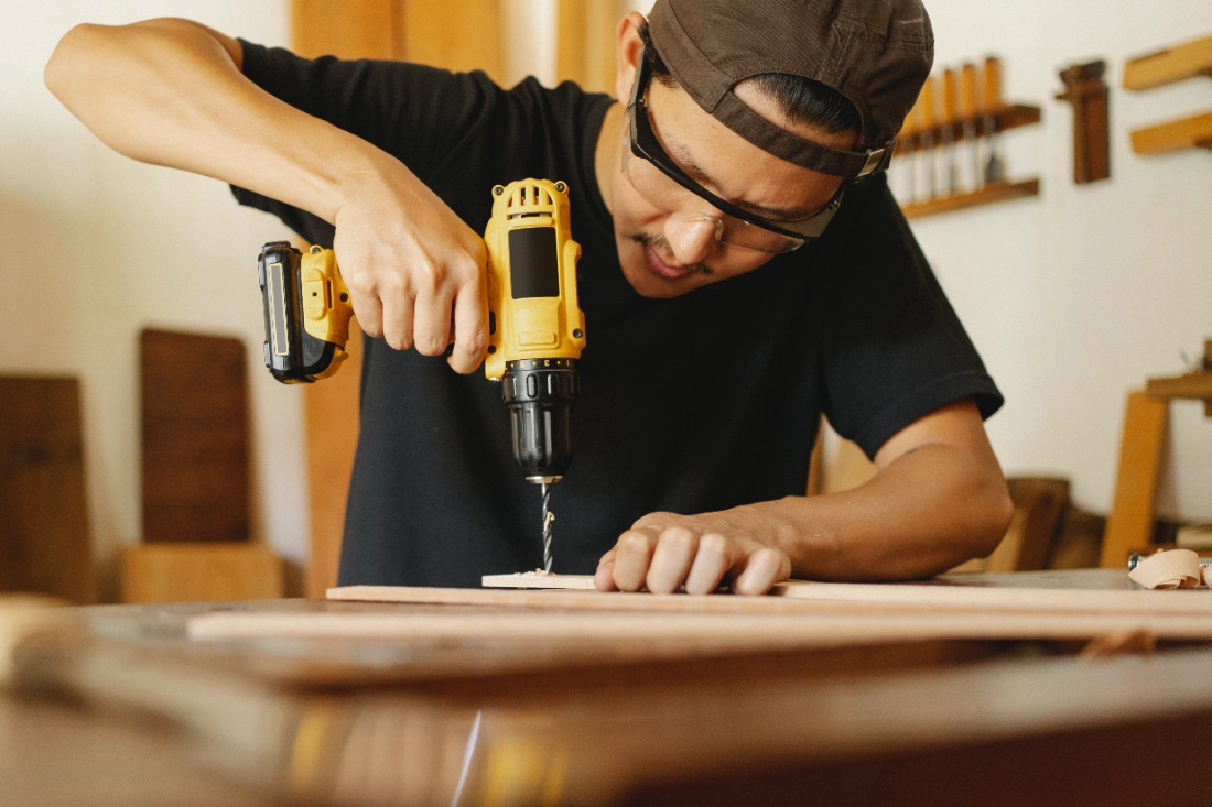 A man using a power drill on wood. 