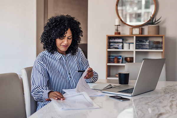 Business owner working on laptop with notepad.