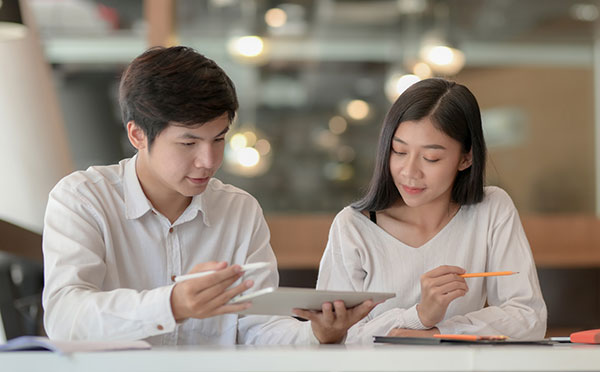 man and woman working on tablet